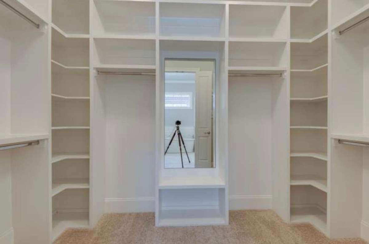 Interior view of primary bedroom closet and wood closet organization system.