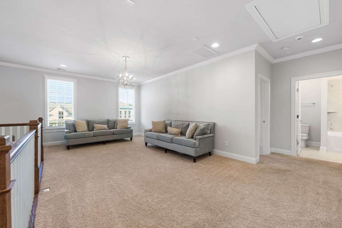 Large upstairs bonus room offers large front facing windows, overhead recessed lighting, access to a full bath and access to drop down attic storage.