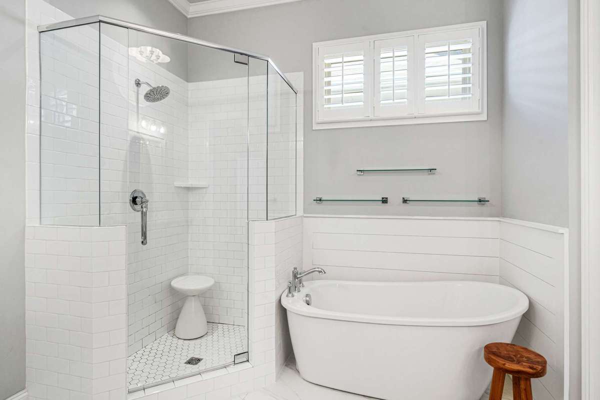 Separate tub (with wood panelling) and large tiled shower in the primary bathroom suite shown here.   Separate door to private water closet adjacent.