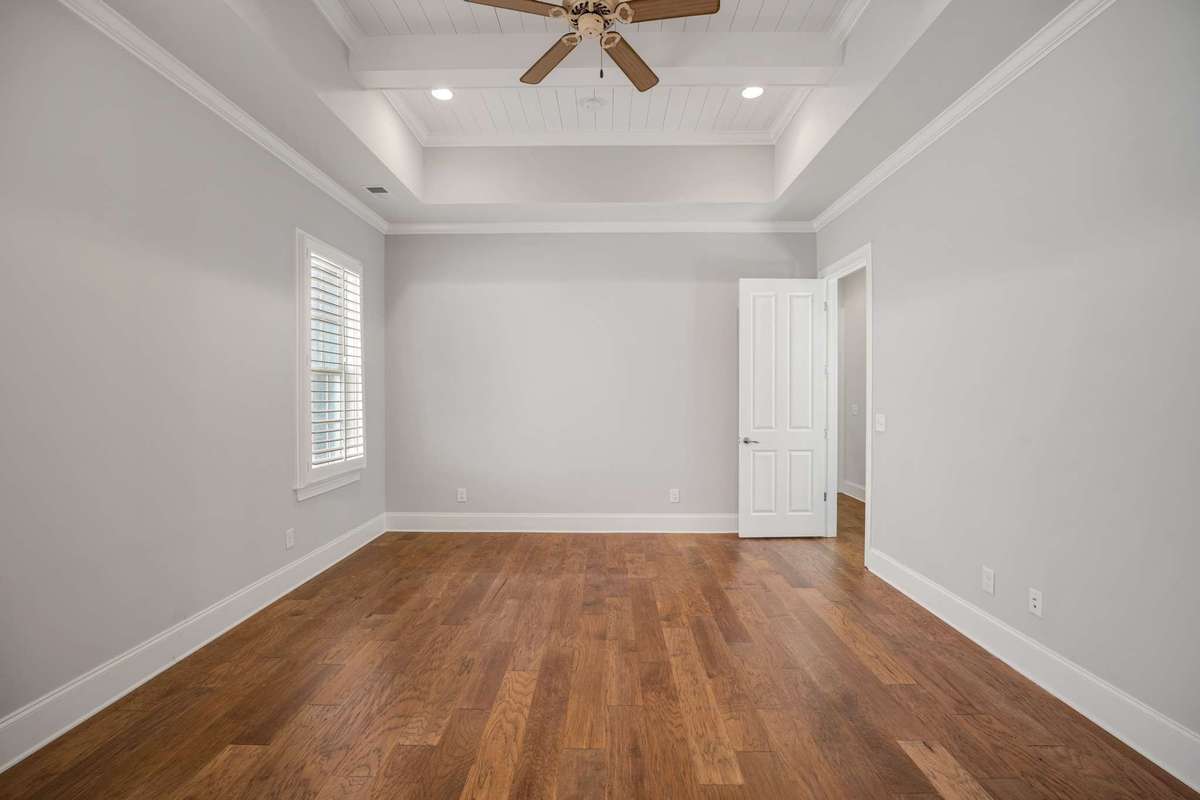 The primary bedroom suite is located on the first floor and features a custom tall trey ceiling feature.