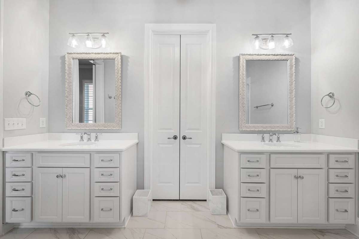 View of the primary bathroom - dual vanities, and French doors into the walk in closet.