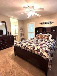 Primary Bedroom has neutral colored carpeting and ceiling fan with lighting kit.