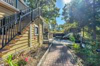 The brick walkway connects the open parking, outdoor shower and storage building to the rear living spaces