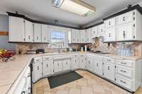 Kitchen with tile flooring, tile countertops, cooktop, dishwasher, built in oven, lots of cabinetry, pantry and adjacent to the spacious breakfast room.