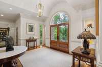 This welcoming foyer has built in glass bookshelves on either side of the door and a barreled ceiling, creating an elevated space to welcome visitors.