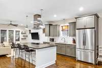Custom soft-close cabinetry, granite countertops, a large island with seating, and stainless-steel appliances