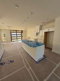 Spacious kitchen featuring a large center island, white cabinetry, and a modern open layout filled with natural light.