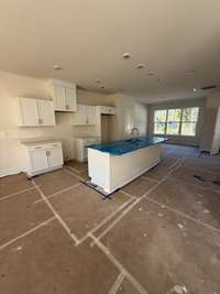 Bright, open kitchen with white cabinetry, a large island, and expansive windows filling the space with natural light.