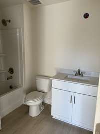 Timeless bathroom featuring a white vanity, sleek fixtures, and warm flooring.