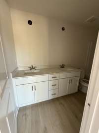 Timeless bathroom featuring a white vanity, sleek fixtures, and warm flooring.