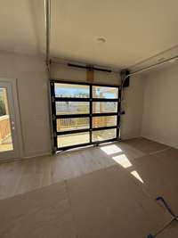 Bright living room featuring a glass garage-style door that opens to a spacious deck with outdoor views.