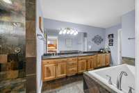 Primary bathroom with a slate shower, stunning custom cabinets with granite countertops!! Dual sinks and a large jetted tub!!