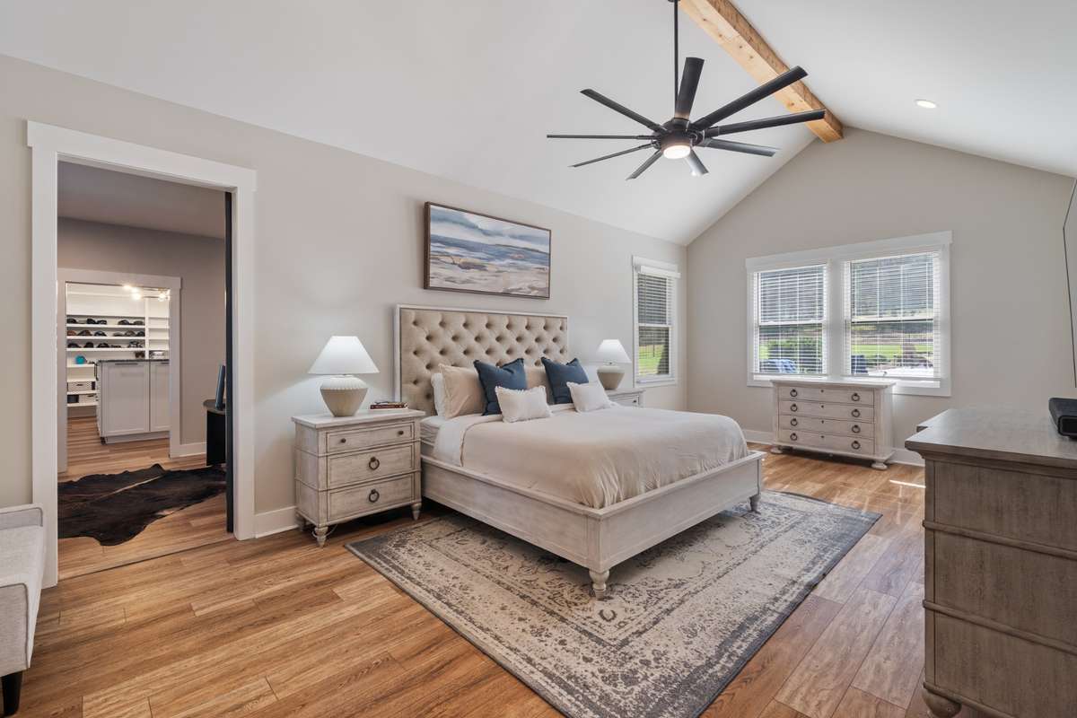 Relaxing primary suite with vaulted ceilings, warm natural wood tone floors, and abundant natural light—your perfect retreat at the end of the day.