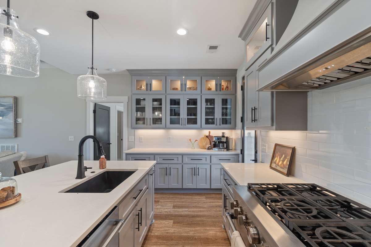 Quartz countertops, tile splash back and glass cabinet doors finish the decor of this kitchen with classic and timeless finishes.