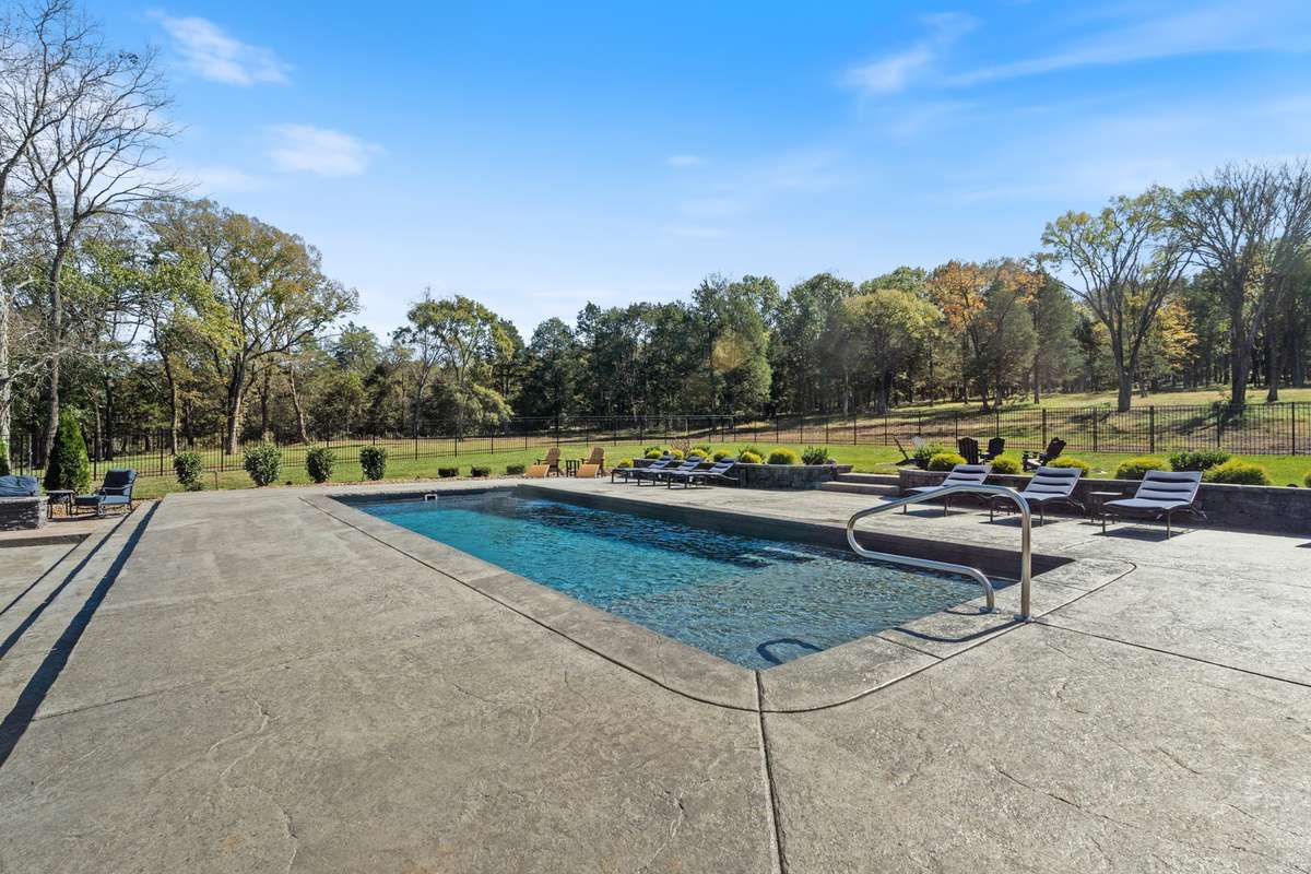 Custom landscaping around the back of the home and pool deck with stone detail stepping into the back yard.