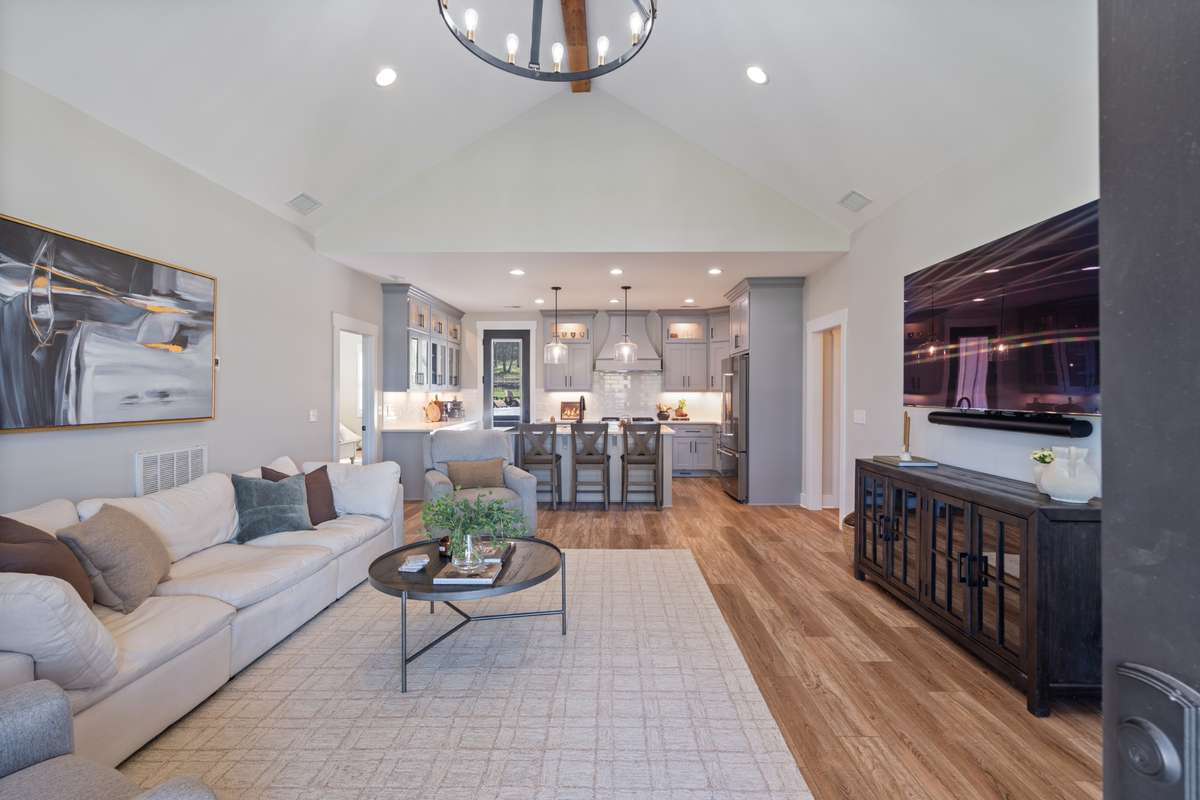 Open-concept layout connects the living room and kitchen for effortless entertaining, with warm natural wood tone flooring, and a spacious island for gathering.