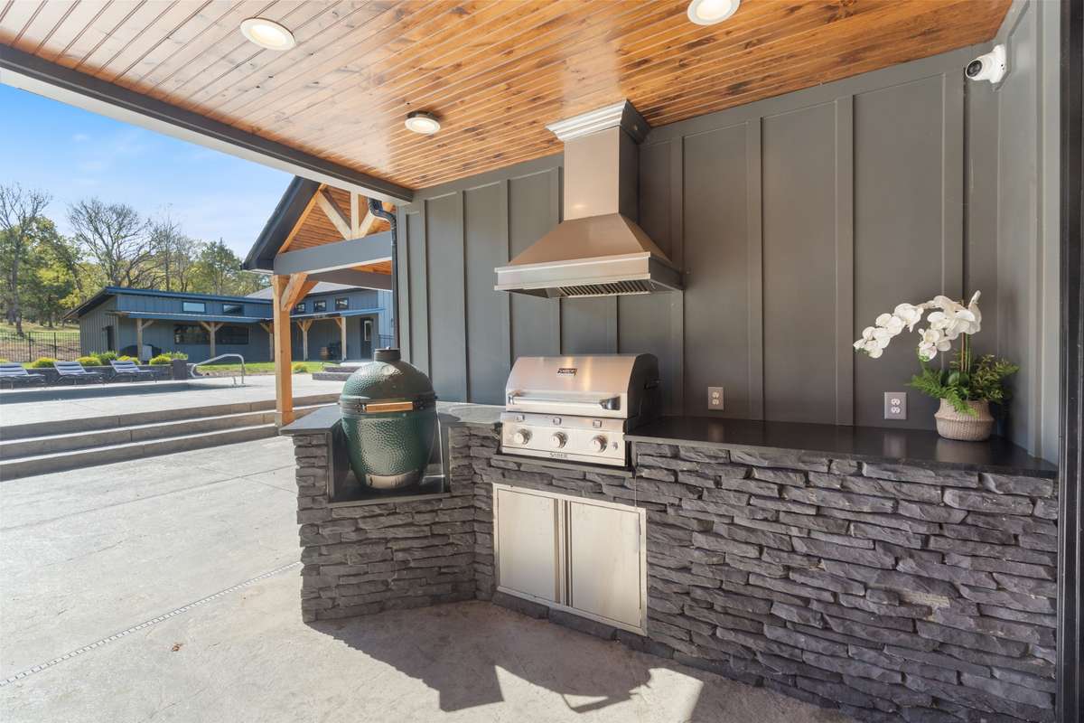 Outdoor kitchen with a built-in grill, stone surround, and covered prep space—made for weekend cookouts and easy entertaining by the pool.