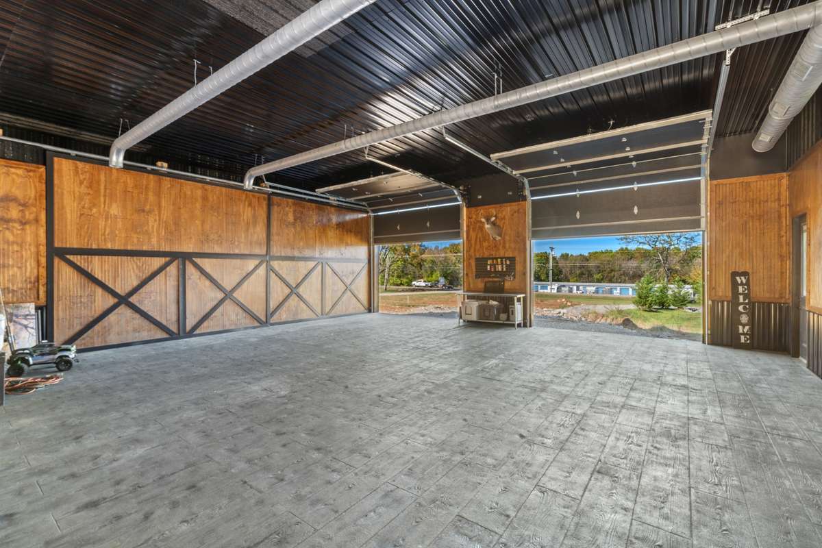 Stamped concrete flooring, custom wood work and sleek black ceilings give this barn an elevated style. There is an additional room adjacent to the wetbar/ kitchen area, perfect for a gym. Plumbing rough in for a future 1/2 bath.