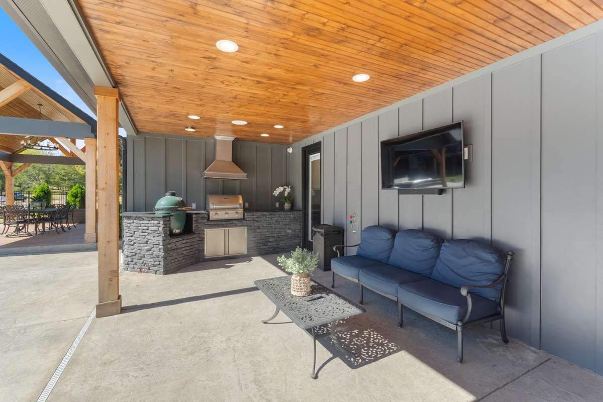 Covered outdoor living area with a wood-plank ceiling, built-in grill station, and space to lounge—perfect for hosting, grilling, and relaxing year-round.