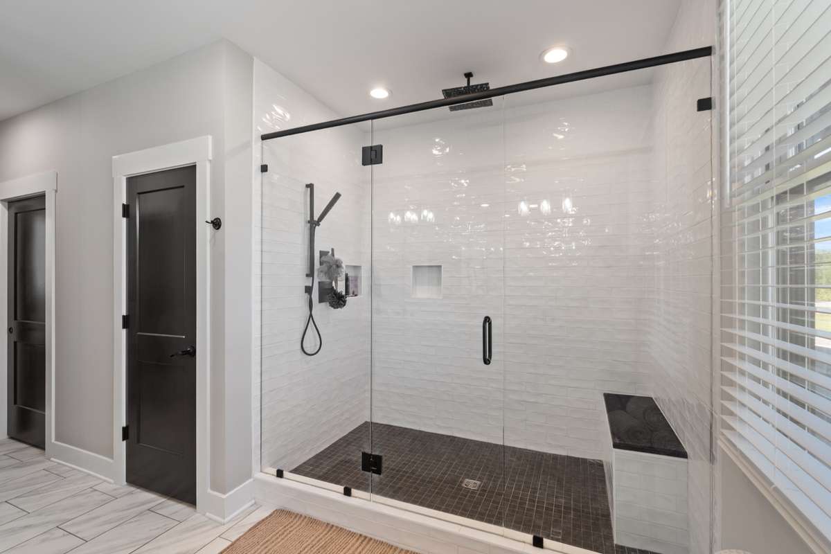 Stunning walk-in shower with floor-to-ceiling tile, sleek glass enclosure, and a built-in bench—your own spa-like escape at home.