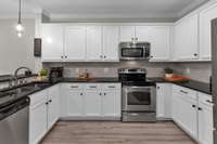Bright kitchen with white cabinetry and stainless steel appliances.