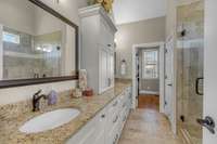 Primary bathroom with double vanities, custom cabinetry, large shower and private water closet. Leading to the large walk-in closet.