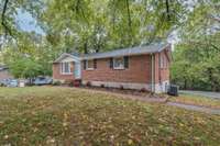 Long driveway down the side of the home that leads to a large parking area in the back, along with a 2-car garage.