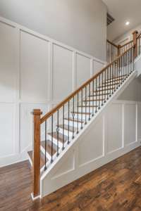The foyer boasts board and batten accents, iron spindles on the staircase and hardwood steps.