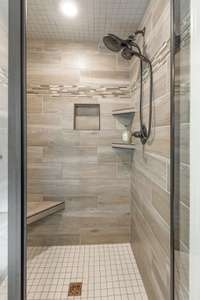 The tile shower has a niche, a shelf and a bench.