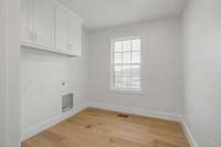 Large Laundry room featuring window for natural lighting, cabinets & linen closet.