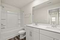 Upstairs hall bathroom with double vanities and a tub/shower combo.