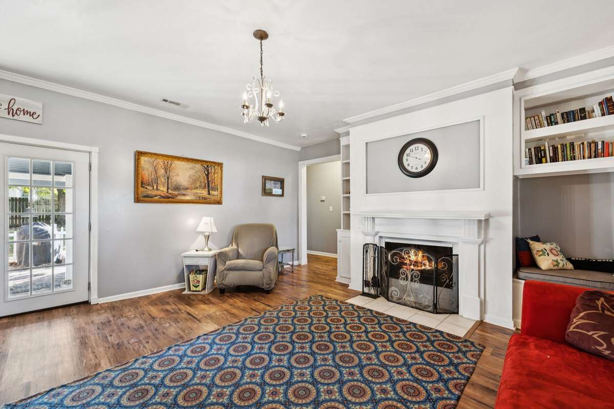 Spacious living room with hard wood style flooring, Hanging chandelier, and cozy fireplace.  3007 Fullerton Ln College Grove Tn 37046