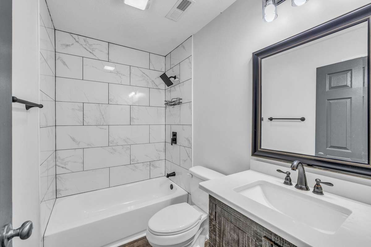 Hall bathroom has tile shower and LVP flooring, original tile is under the LVP.