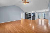 Step into the spacious living room featuring stunning hardwood flooring and a vaulted ceiling, creating an airy and open atmosphere.