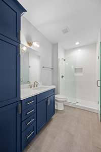 The downstairs primary bath features a tiled walk in shower,