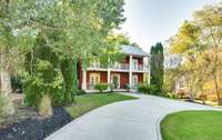 Lush landscaping wraps this residence it greenery. A durable metal roof sits atop this all brick home.