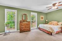The serene primary bedroom overlooking lush trees and a rural landscape - a perfect morning retreat.