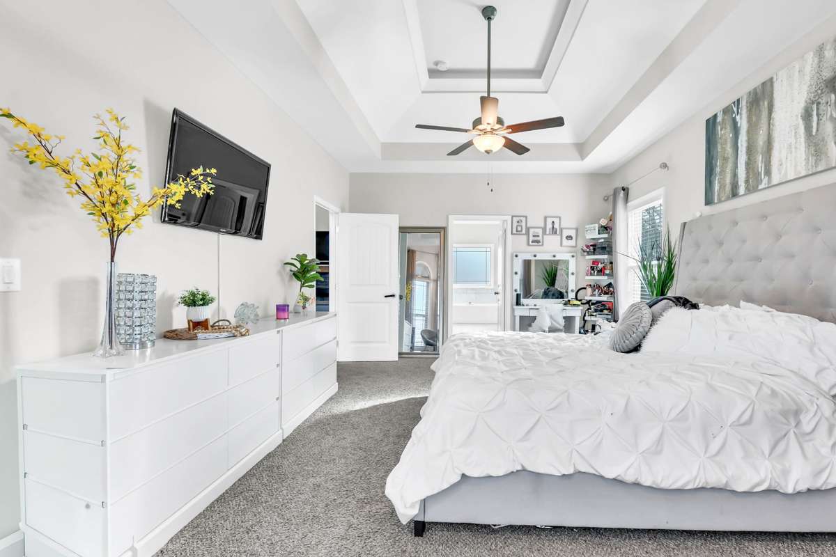 Downstairs primary bedroom with double tray ceilings and sitting area.