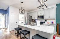 Kitchen has a large island with barstools remaining