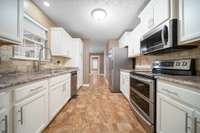 Modern kitchen featuring stainless steel appliances, ample cabinetry, a large sink, and an elegant wall-to-wall tile backsplash.