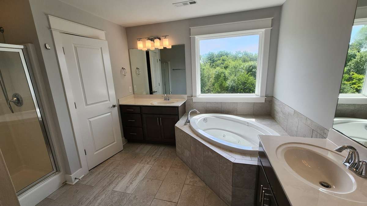 Spacious primary bathroom with upgraded jetted tub, tile flooring, and dual sink vanities...like having your own spa!