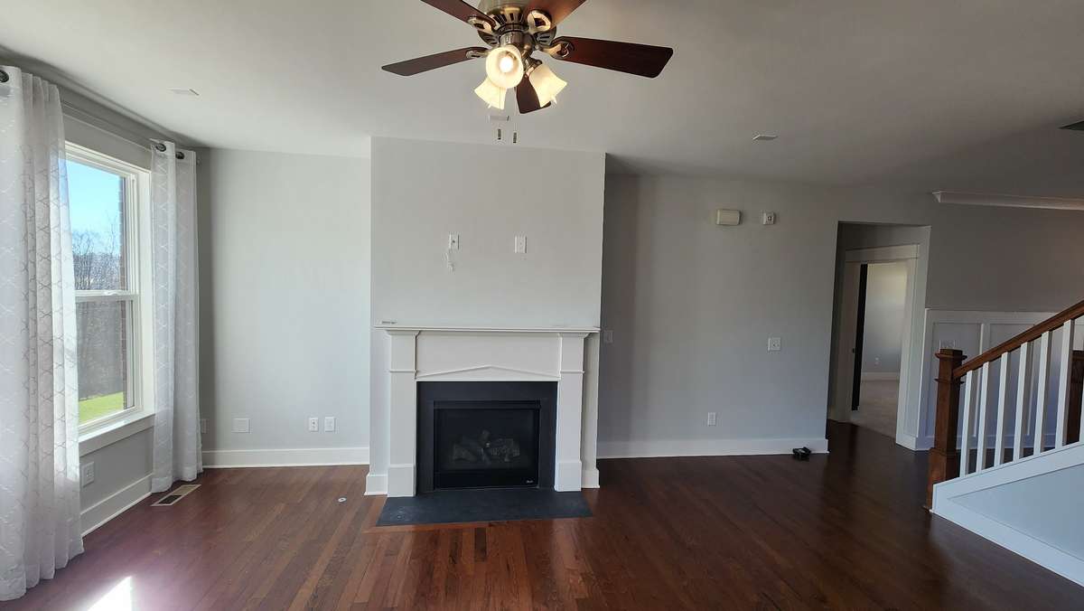 Large living room window allows sunlight to shine on those gleaming hardwood floors throughout and check out that gas fireplace!