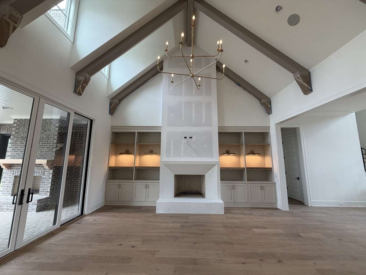 Vaulted Great Room with wood burning fireplace and built-ins. *this home is under construction.  Photo taken: 4/6/26
