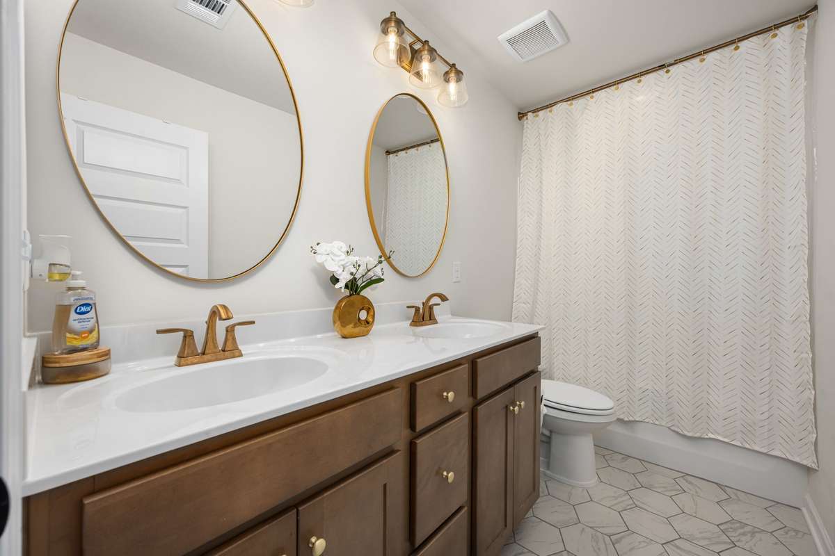 Dual vanities in the upstairs bathroom with tub/shower combo.