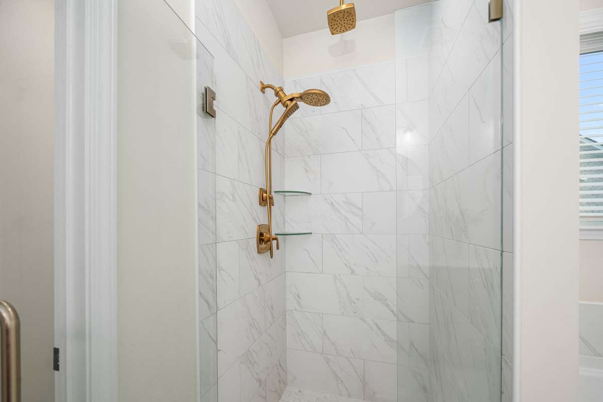 Walk in tile shower with glass door.