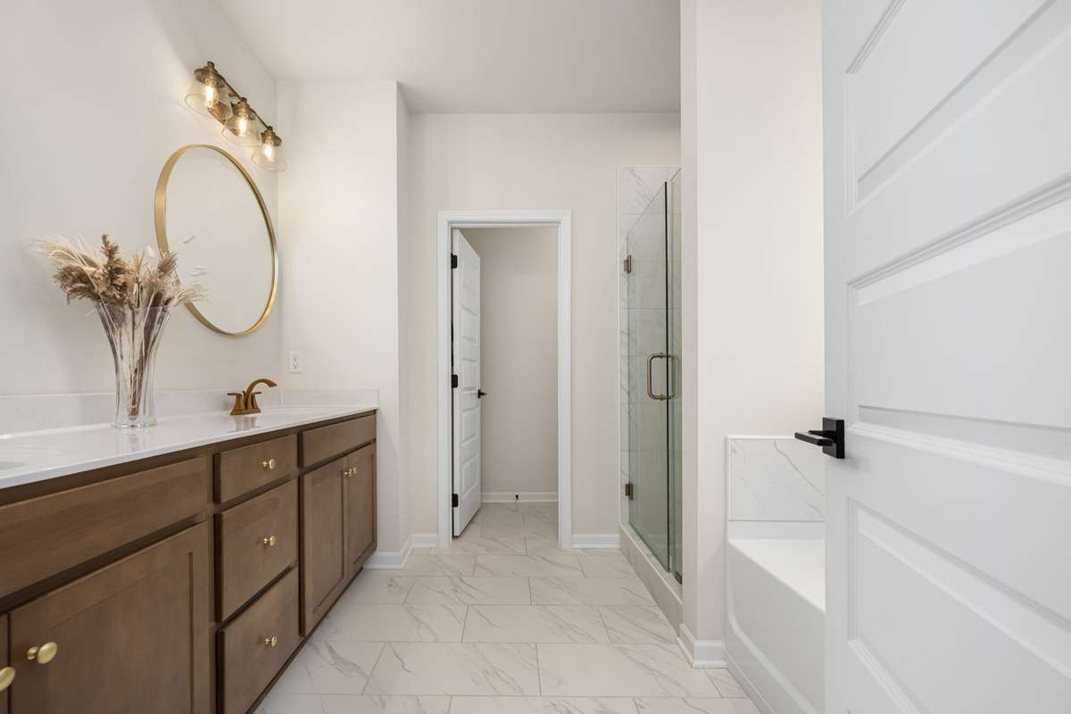 Double vanities, spa-like tub, tiled shower with frameless glass shower door and separate toilet area.