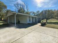 Covered carport with a storage closet, plus a wide driveway for plenty of parking.