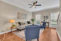 The living room features two windows with blinds, crown molding and neutral paint.