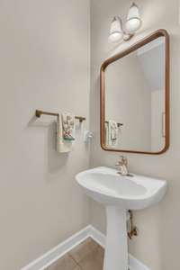 The powder room features an updated mirror and pedestal sink.