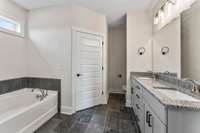 The luxurious bathroom with over-sized dark gray tiles, dual-closets and a double vanity!